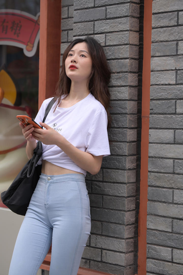 靠在墙上发呆的日韩清纯紧身裤美女街拍图片