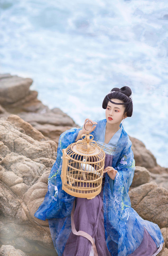 海边提着鸟笼的古装美女艺术写真图片