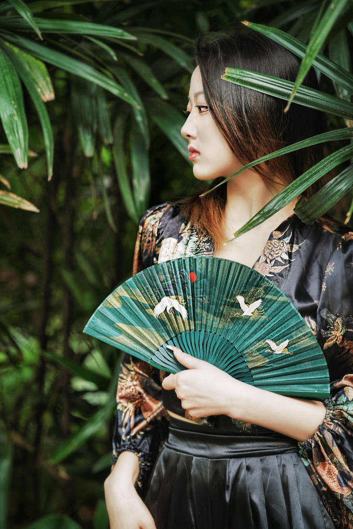 手持纸扇的气质美女模特户外写真摄影图片