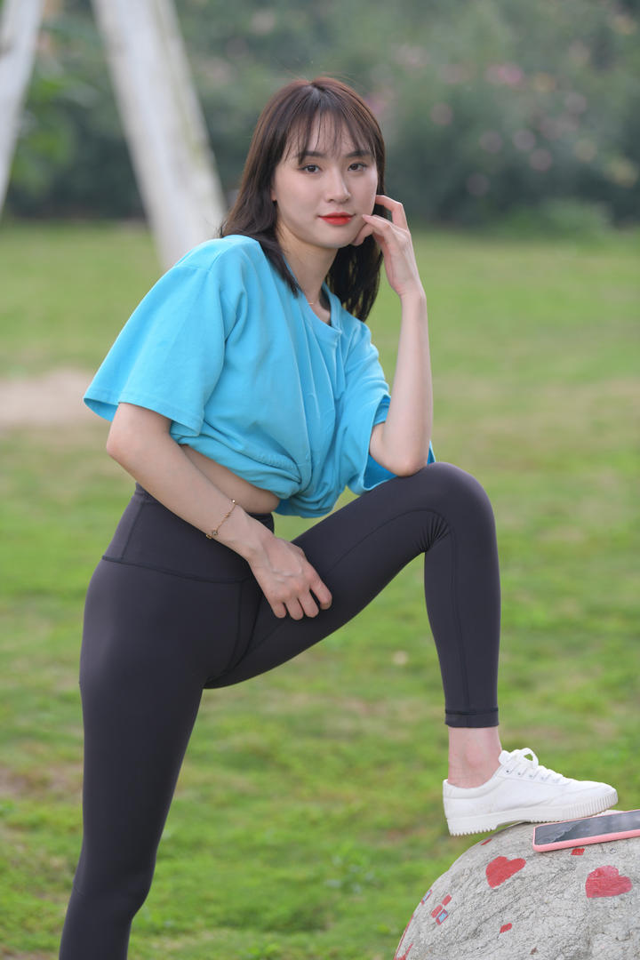 张开腿踩在石头上的黑色紧身裤美女图片