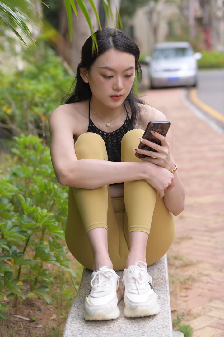 坐在街边玩手机的漂亮紧身裤美女图片