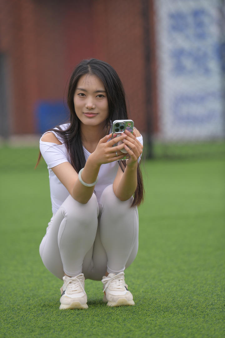 蹲在草地上的美女紧身裤写真图片