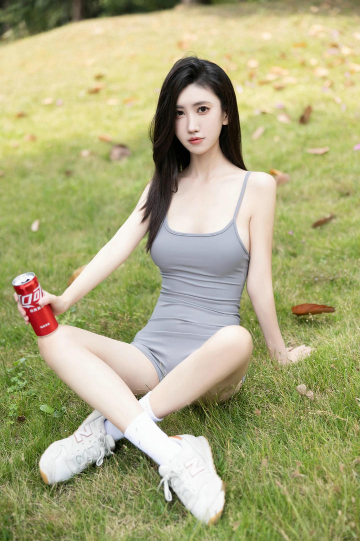 草地上喝可乐的吊带紧身裤美女模特中国美女图片