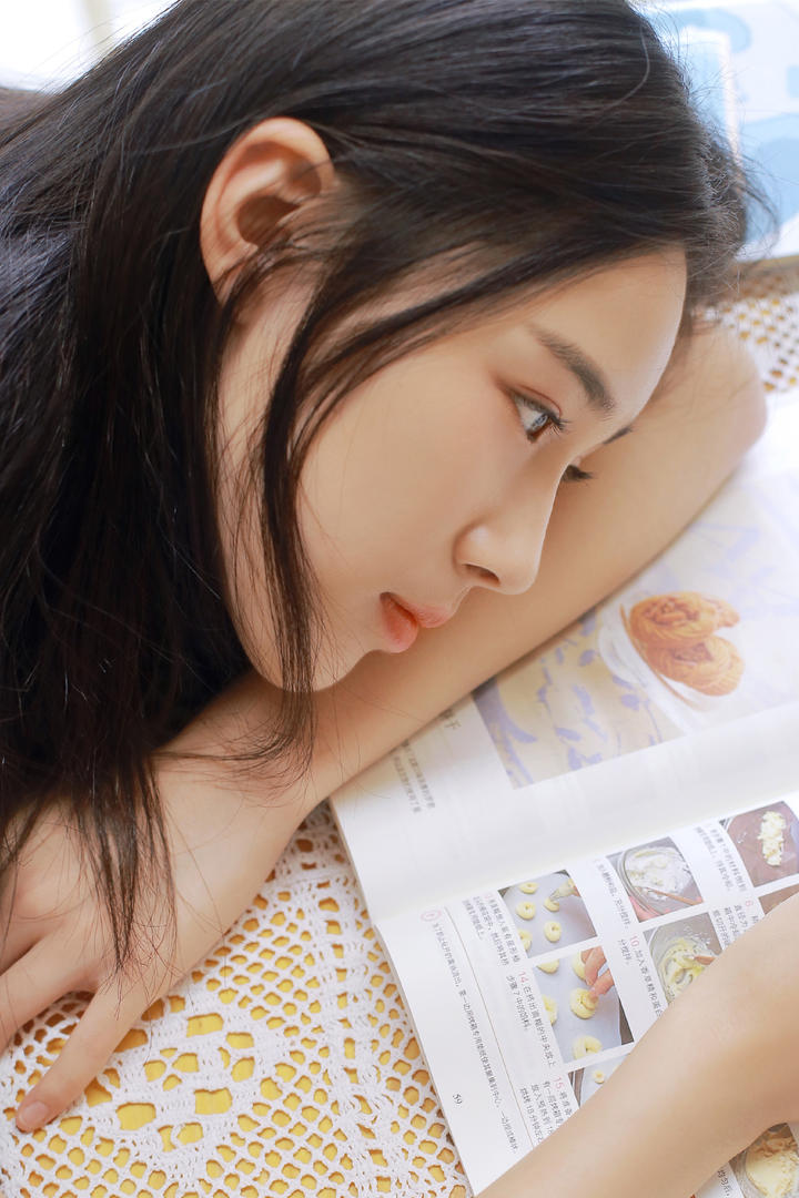 趴在桌子上看食谱的青春美少女图片