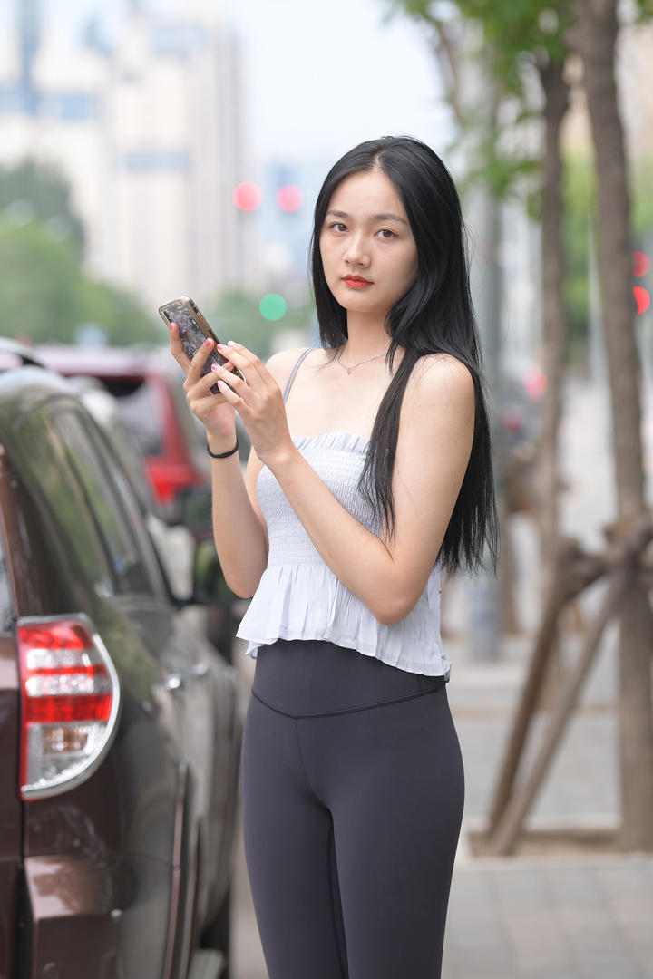 街拍玩手机的紧身裤美女写真图片