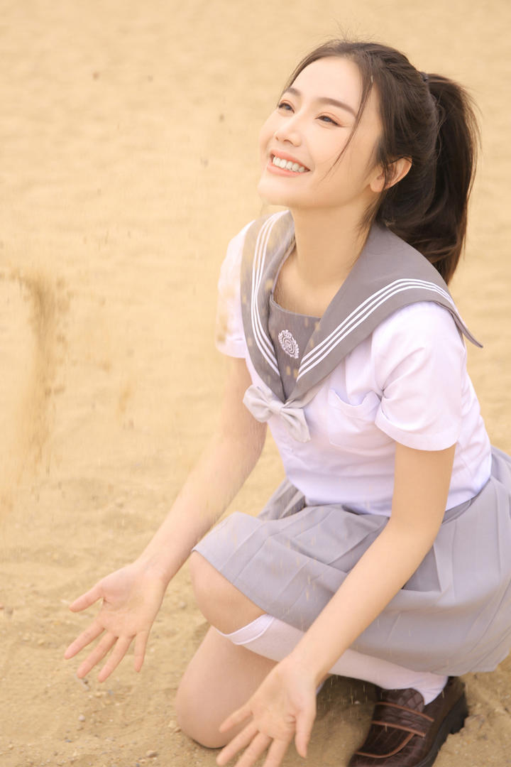 蹲在沙子上的校服美女图片