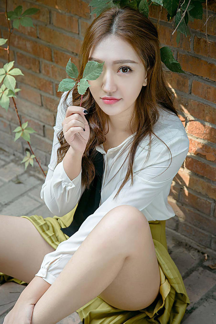 拿着树叶坐在地上的高清美女图片