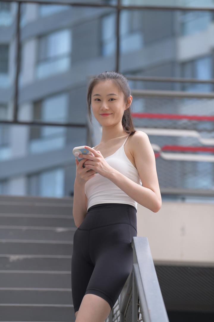 靠在栏杆上玩手机的清纯瑜伽裤美女街拍图片大全