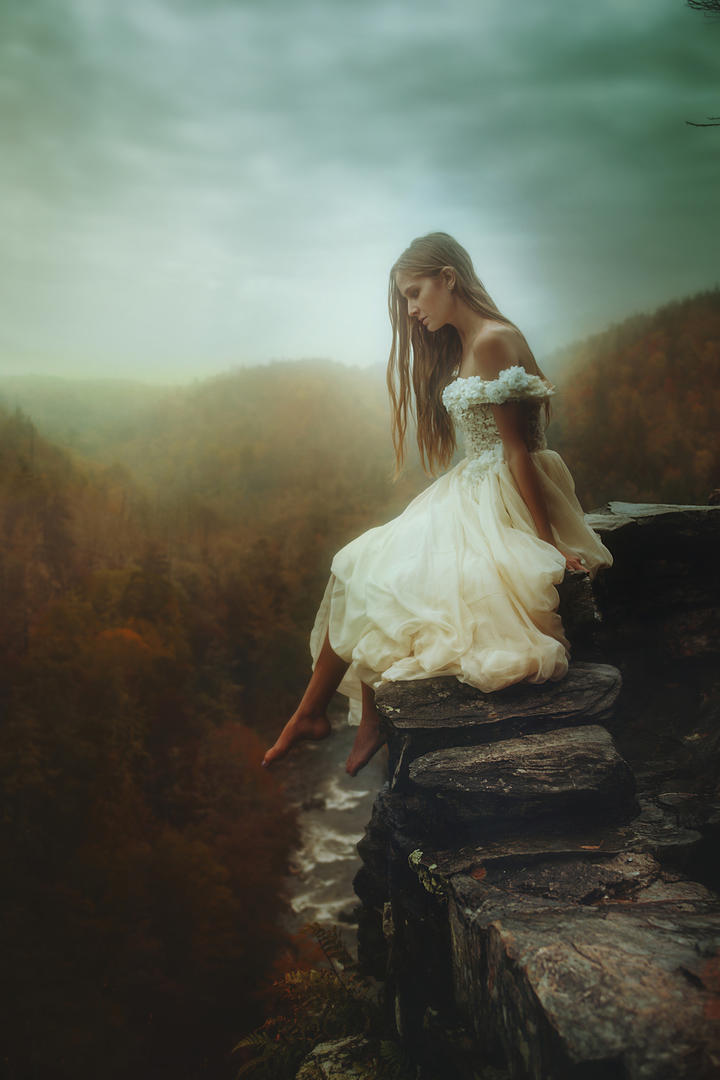 坐在悬崖边的白裙美女图片