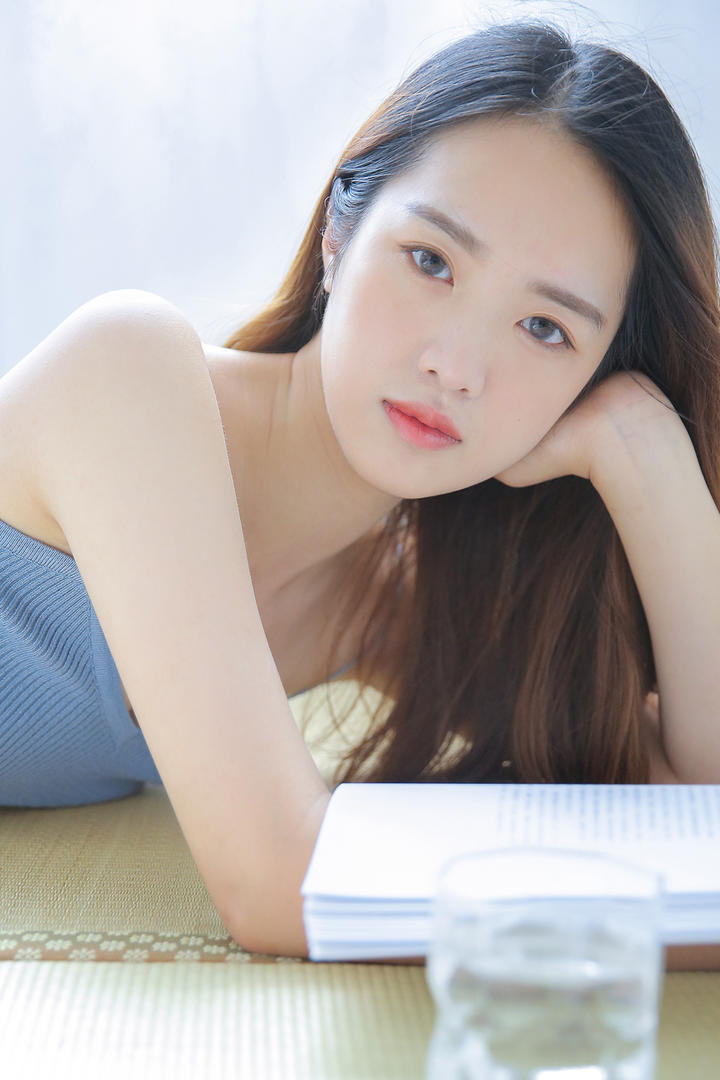 趴在席子上看书的清纯美女图片