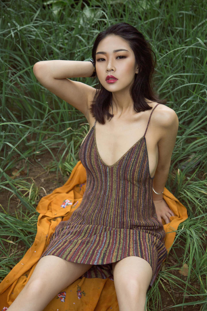 坐在草地里的吊带短裙美女图片