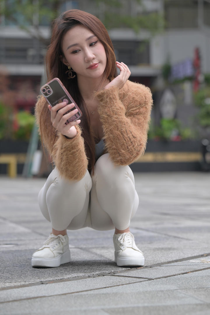蹲在街上玩手机的紧身裤美女图片