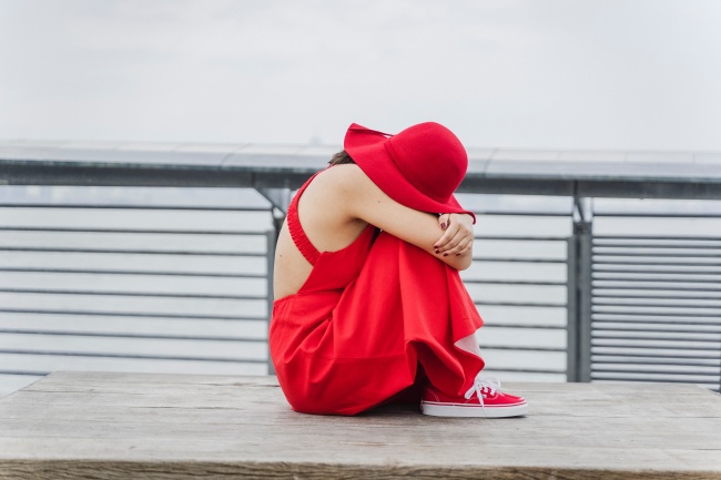 坐在木凳上抱腿的红衣女人图片