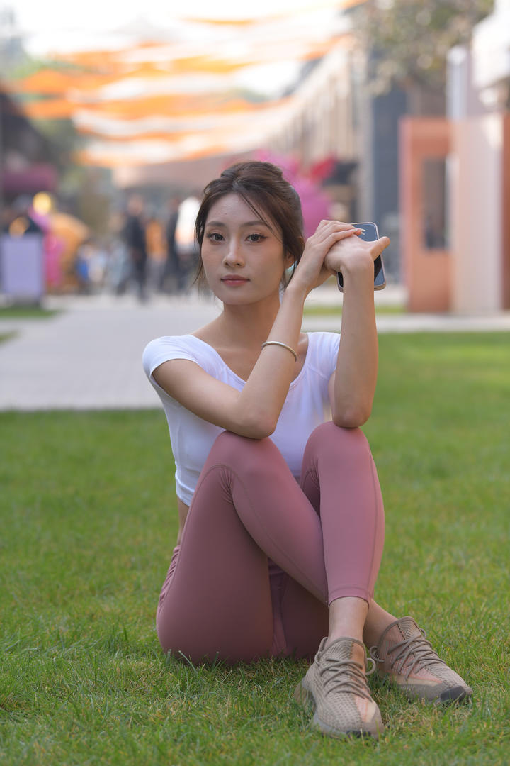 坐在草地上的粉色紧身裤美女性感图片