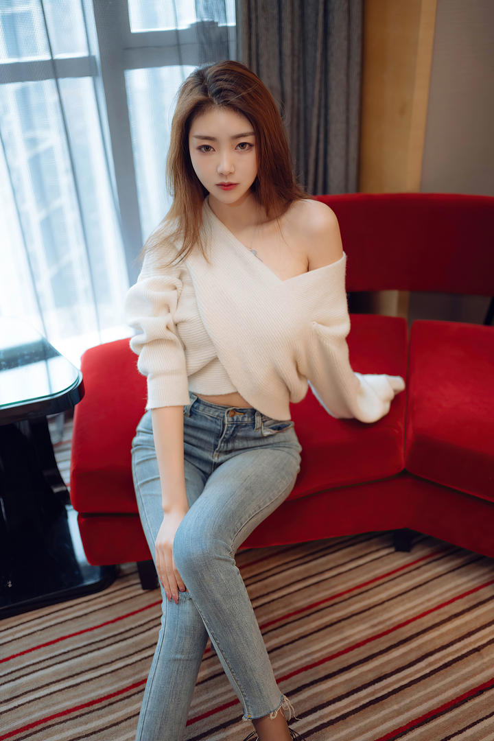 坐在红色沙发上的牛仔裤美女可樂高清图片
