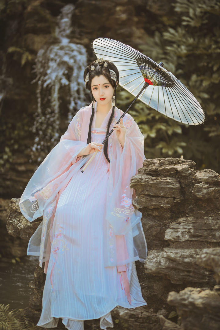 假山上撑着伞的古装美女艺术写真图片