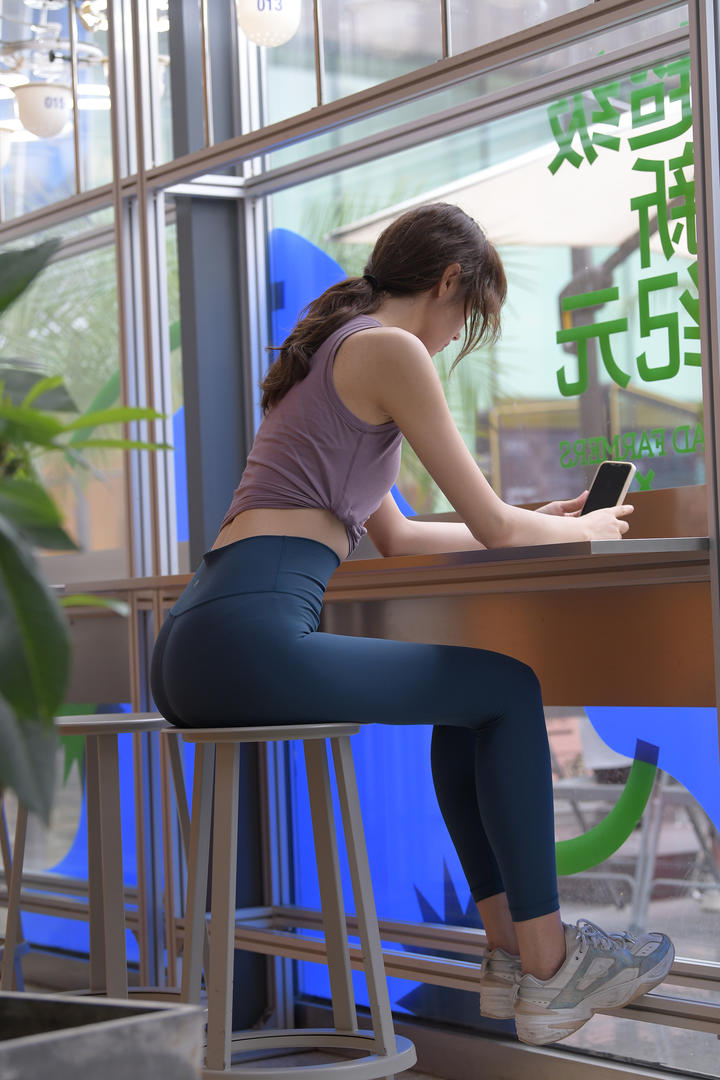 奶茶店里玩手机的紧身裤美女3a街拍图片